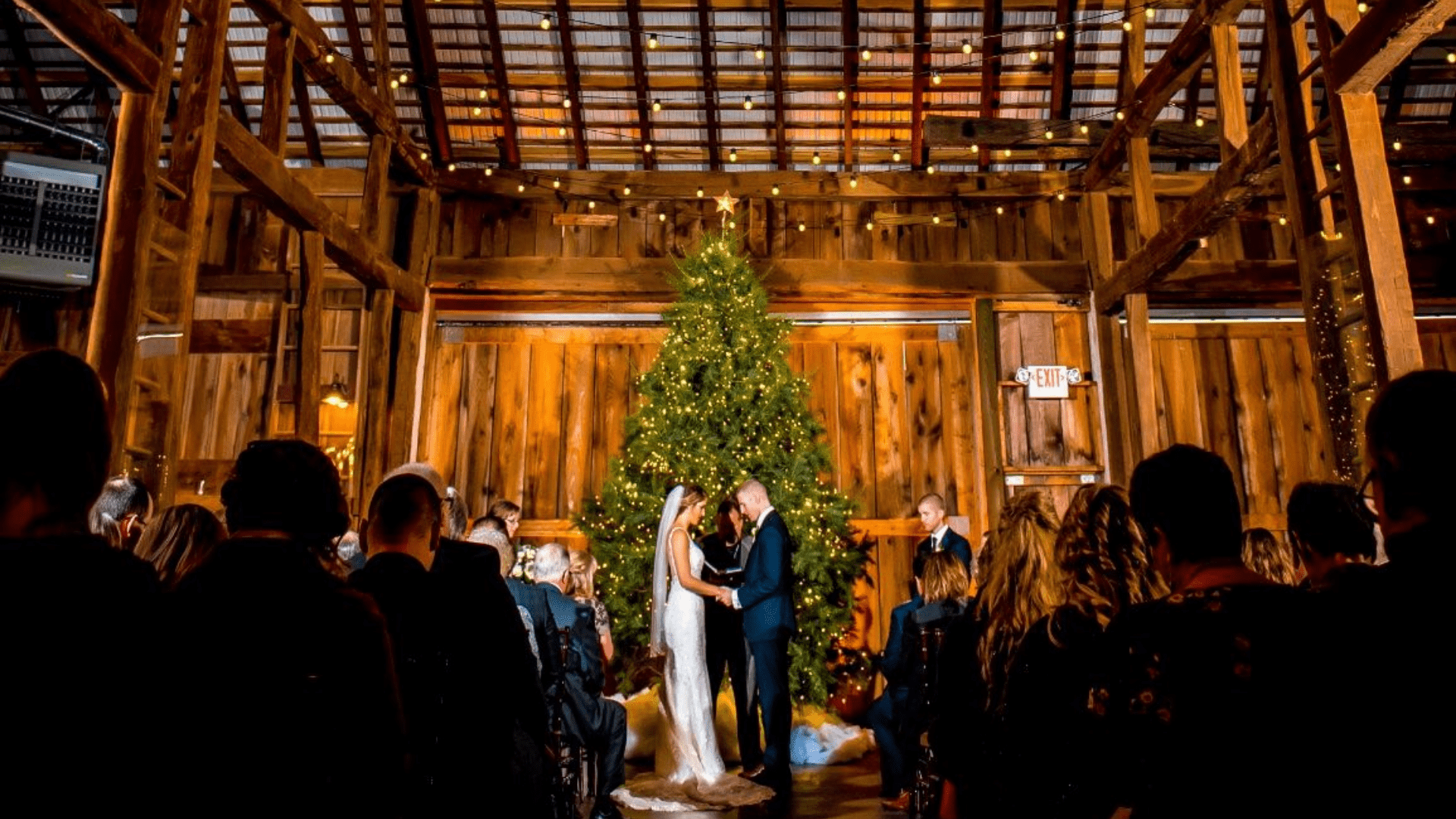 Couple at an altar with a christmas tree in rustic barn wedding venue